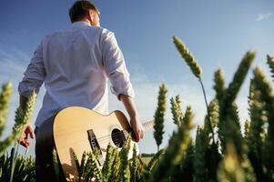 Musician is ,with acoustic guitar. Man in white shirt is on the agricultural field photo