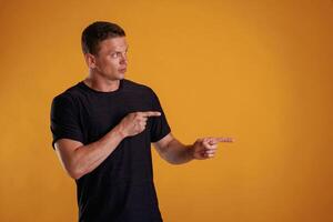 Showing ,,to the side, pointing.,, Man is ,against background in the studio photo