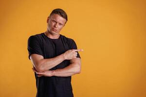 Showing to the side, pointing. Man is,,, against background in the studio photo