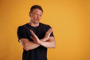 Hard dislike, showing stop or no by the hands. Man is against background in the studio photo