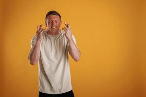 Fingers crossed, hoping ,for ,the luck. Man is against background in the studio photo