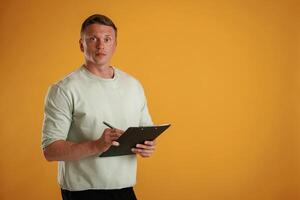 With notepad and pen... Man is against background in the studio photo