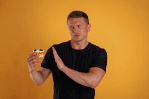 Say, no, to ,sugar, holding cake, don't like it. Man is against background in the studio photo