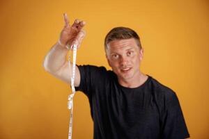 Measuring tape in hand, fitness conception... Man is against background in the studio photo