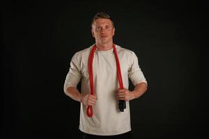 Red jump ropes, endurance and, sport concept. Man is against background in the studio photo