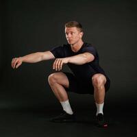 Squats exercise. Man is against background in the studio photo