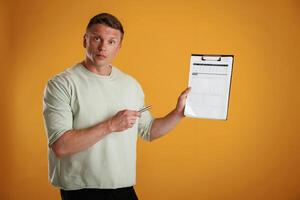 Results, data in, the ,notepad, holding it. Man is against background in the studio photo