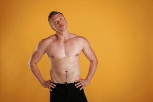 Shirtless, standing.. Man is against background in the studio photo