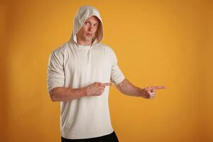 Product on the side, copy space, pointing. Man is against background in the studio photo