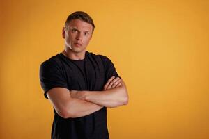 Standing with, arms crossed. Man is against background in the studio photo