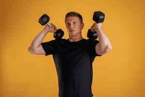 Lifting dumbbells. Man is against background in the studio photo