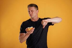 Say ,no, to sugar, holding cake, don't like it. Man is against background in the studio photo