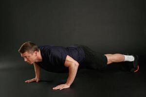Push ,,ups exercise. Man is against background in the studio photo