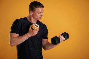 Dumbbell,, or cake, choice. Man is against background in the studio photo