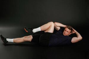 Abs exercise. Man is against background in the studio photo