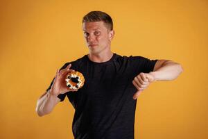 Say ,,no to sugar, holding cake, don't like it. Man is against background in the studio photo