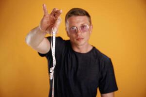 Measuring, tape in hand, fitness conception. Man is against background in the studio photo