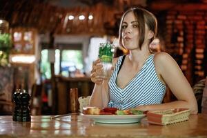 Fresh mojito is in hand..., Woman is in the restaurant with food and drink photo