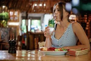 Drinking the mojito.... Woman is in the restaurant with food and drink photo