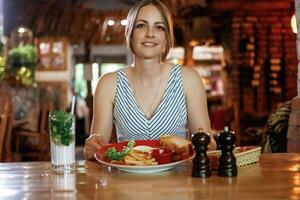 Front view. Woman, is, in the restaurant with food and drink photo