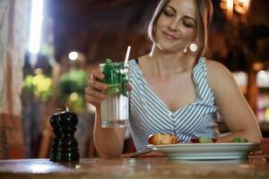 Drinking the mojito.., Woman is in the restaurant with food and drink photo