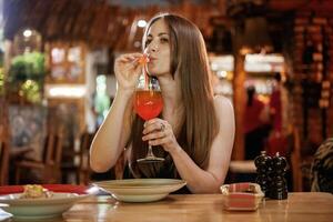 Red ,cocktail, drinking. Woman is in the restaurant with food and drink photo