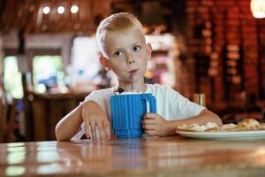 Little, boy is sitting indoors and eating delicious pizza photo
