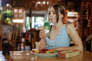 Drinking the mojito. .Woman is in the restaurant with food and drink photo