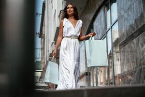Taking a walk.. Stylish woman is with shopping bag outdoors near the building photo