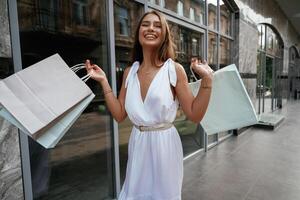 Showing the ,new stuff, smiling. Stylish, woman is with shopping bag outdoors near the building photo