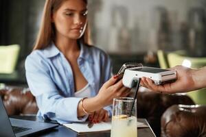 Using, smartphone... Woman is paying for the service in the restaurant photo
