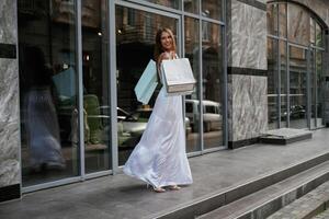 New, things, from the, sale. Stylish woman is with shopping bag outdoors near the building photo