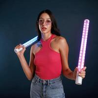 Neon ,lighting equipment in hands. Beautiful young woman is against background photo