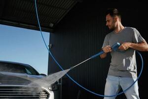Taking care of washing. Man is with his car outdoors.. photo