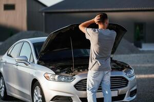 Issue, vehicle is broken.,,, Man is with his car outdoors photo
