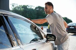 Transport is being cleaned., Washing service. Man is with his car outdoors photo