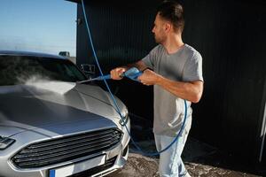 Side view, car wash, high pressure. Man, is wi,,,h his automobile outdoors photo