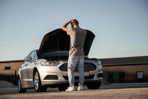 Trying to repair the broken automobile. Man is with his car outdoors photo