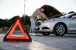 Under the sunlight, red sign, accident, broken automobile, repair. Man is with his car outdoors photo
