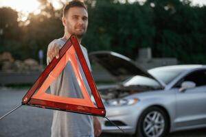 Broken car, red sign. Man is with his automobile outdoors photo