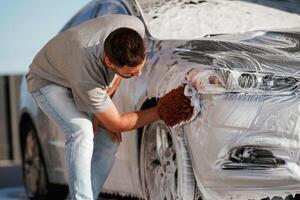 Process of washing ,the ,,automobile. Man is with his car outdoors photo