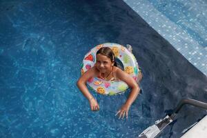 With ,lifebuoy,, learning,, how to swim. Happy little girl is having fun in the pool photo