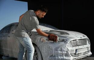White soap and foam, washing, the,, automobile. Man is with his car outdoors photo