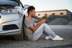 Accident, broken automobile is parked. ...Man is with his car outdoors photo
