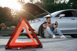 Broken car, red sign. Man is,, with ,his automobile outdoors photo