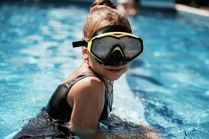 In swimming mask. Happy little, girl, is having fun in the pool photo