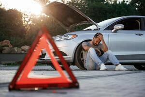 Broken car, red sign. Man ,is ,with his automobile outdoors photo