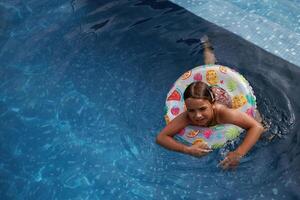 With lifebuoy, learning ,how ,to swim... Happy little girl is having fun in the pool photo