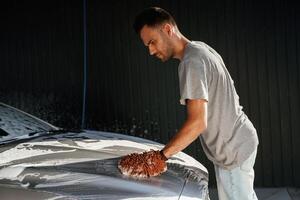 Focused ,at,, washing the automobile. Man is with his car outdoors photo