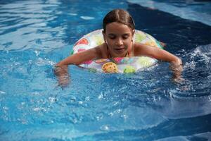 With lifebuoy,, learning, how to swim... Happy little girl is having fun in the pool photo